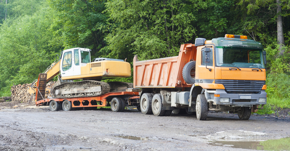Truck with low loader trailer towing a digger